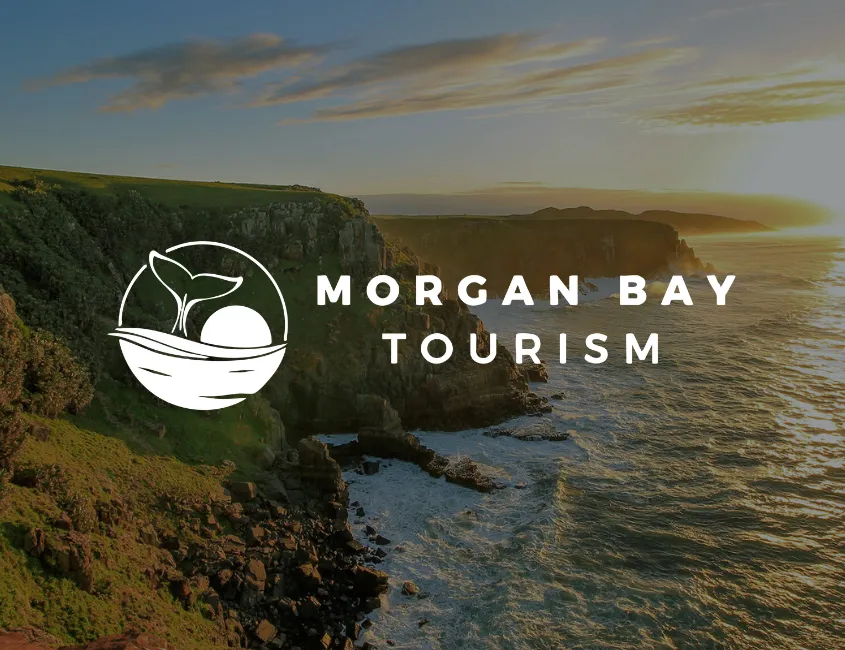 Morgan Bay Tourism logo over the cliffs at sunset
